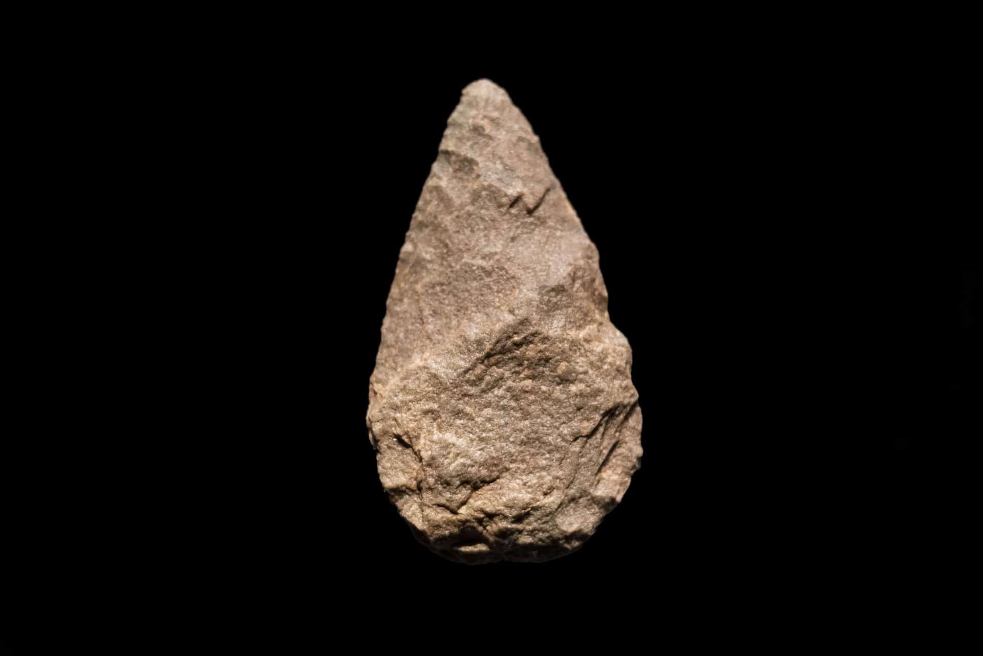 Prehistoric human tool, Quartzite biface on black isolated background, 500.000 years old.