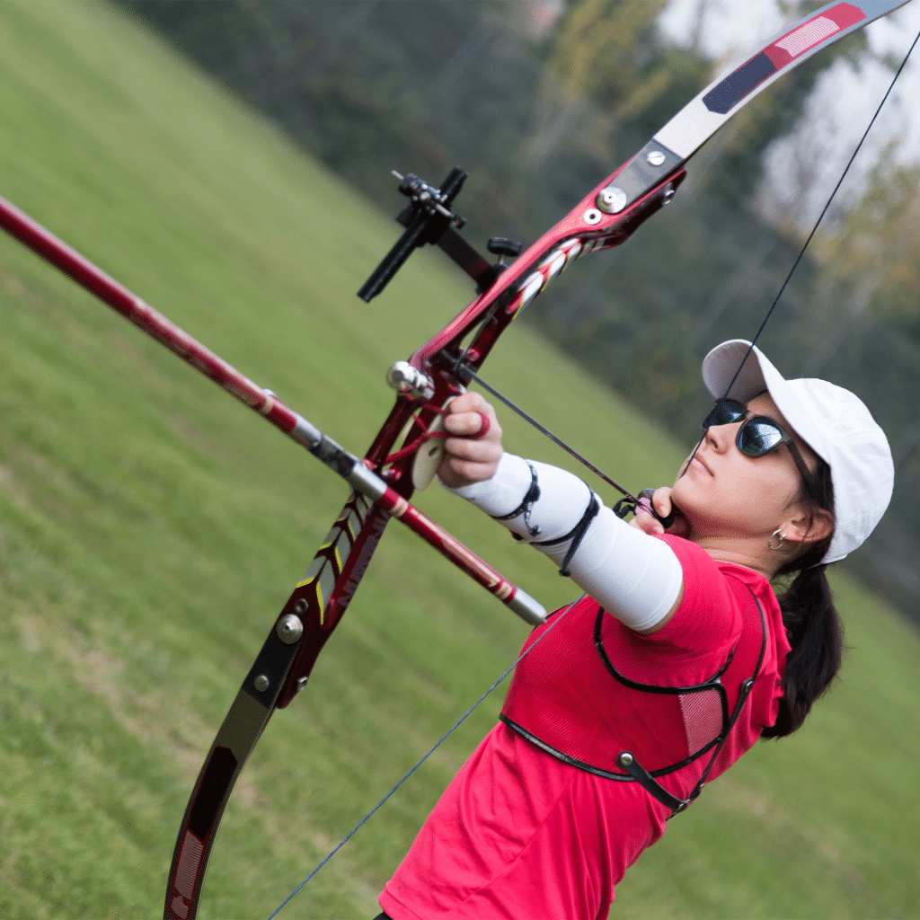 woman wearing glasses and shooting a recurve bow